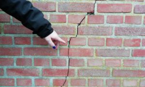 bewoner wijst een scheur in de muur aan
